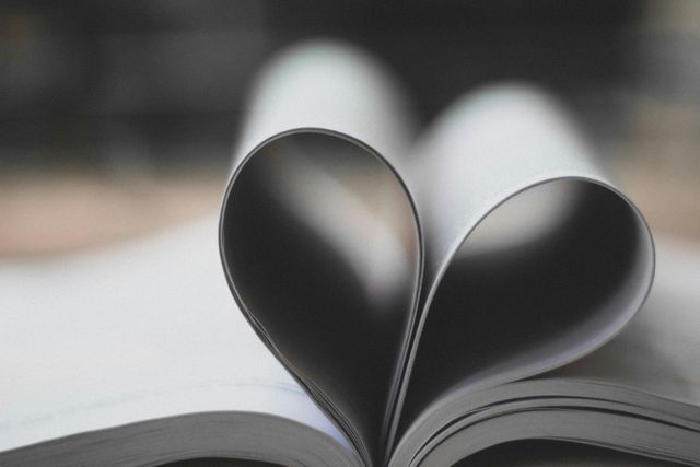 A close up of an open book with the pages folded into a heart shape.